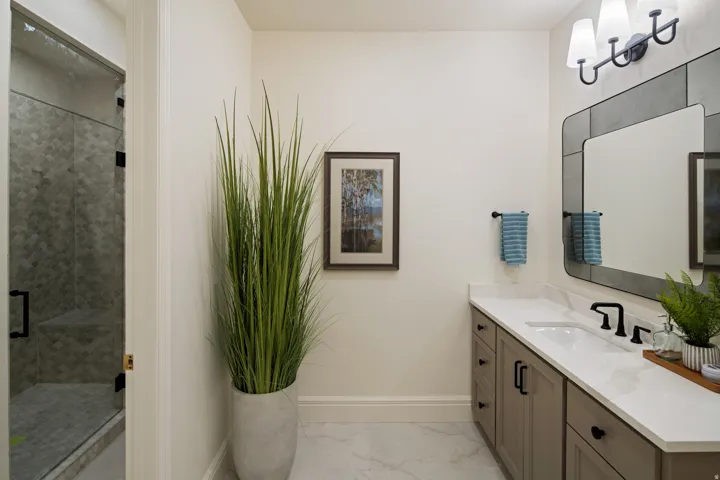 Full bath featuring vanity, a stall shower, and light marble finish flooring