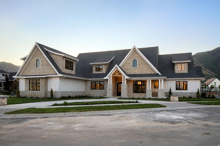View of front of house featuring stone siding, board and batten siding, a shingled roof, and a porch