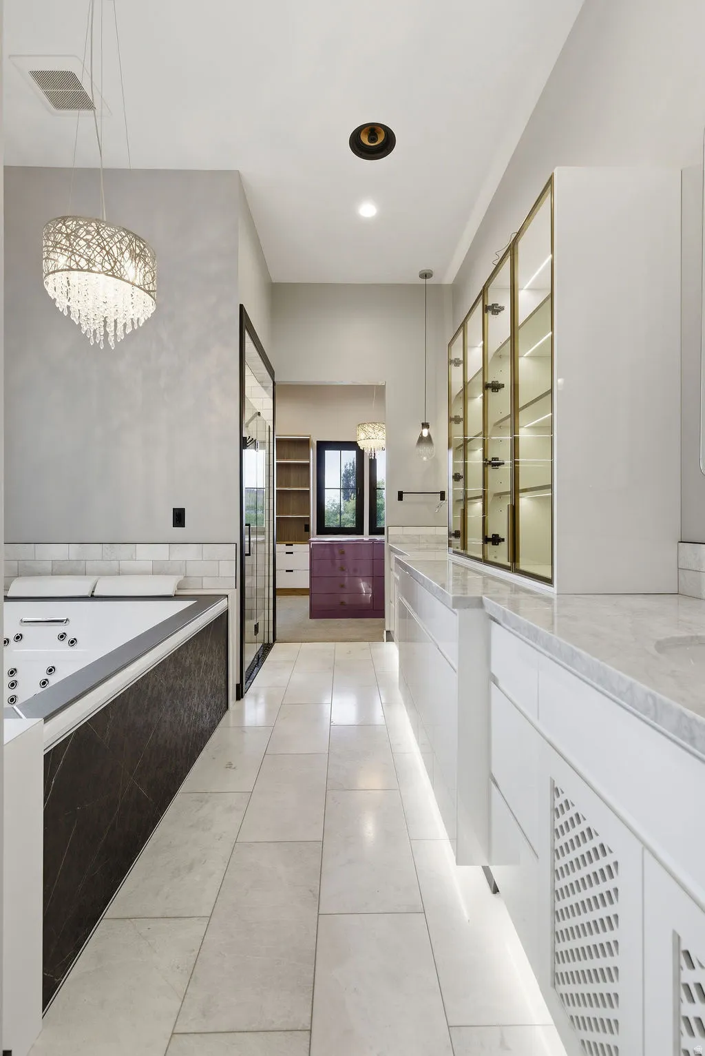 Elongated bath area featuring a built-in jetted tub with dark-toned paneling, a large mirror, and a contemporary chandelier