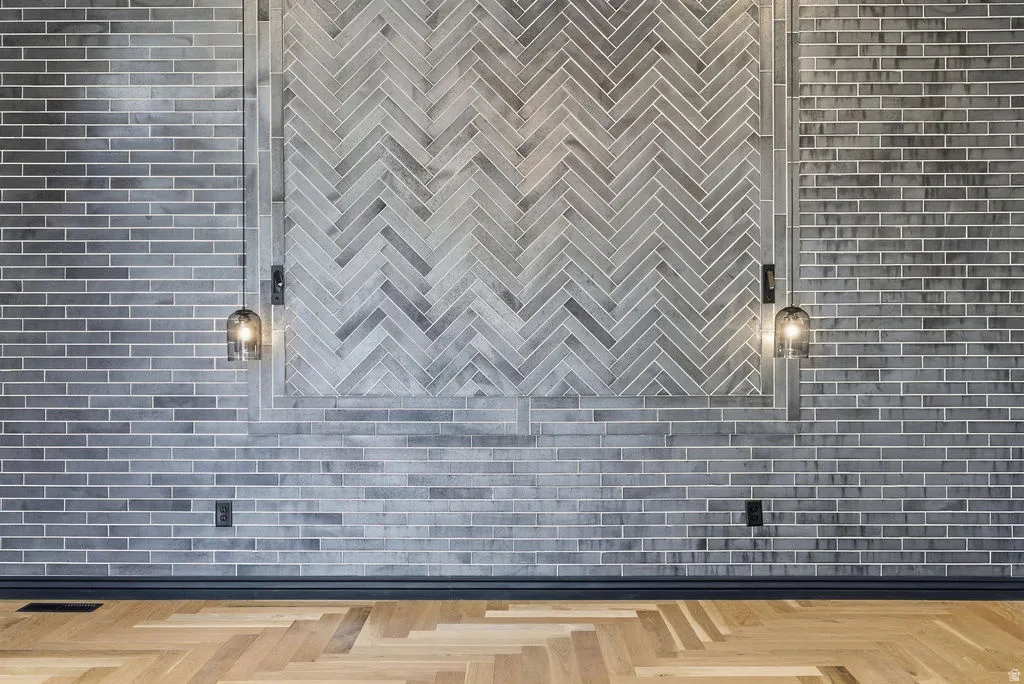 Herringbone wood-finish flooring complements a feature wall with gray subway tile and a central herringbone tile pattern