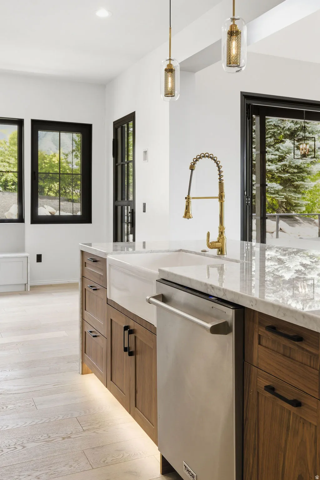 Kitchen island featuring a white apron-front sink, a brass-tone faucet, and stainless steel dishwasher