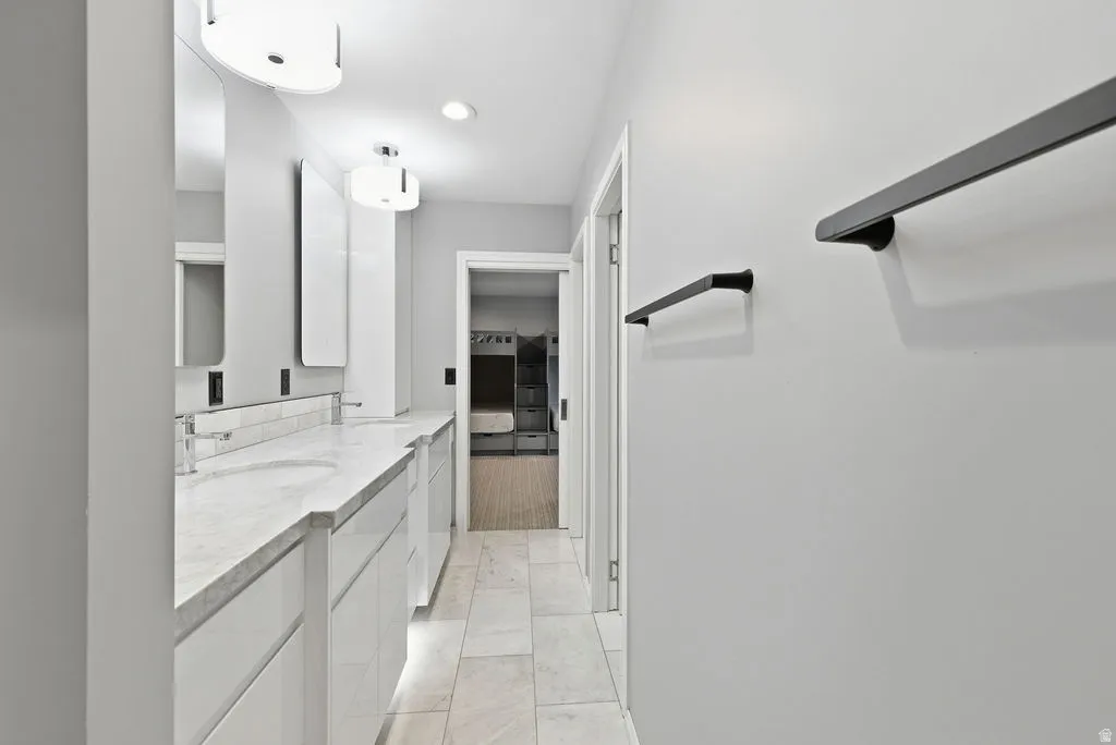 Double vanity with undermount sinks, stone countertop, and tile backsplash