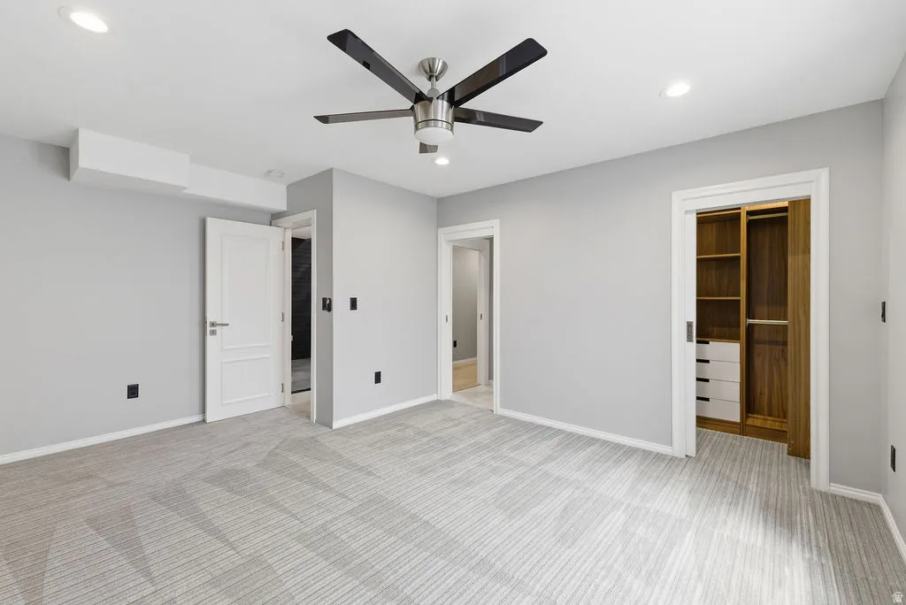 Spacious room featuring light gray walls, patterned carpeting, recessed lighting, and a modern ceiling fan