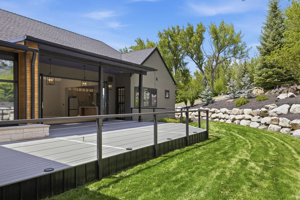 Spacious composite deck with stone accent planter, black railing, and integrated lighting