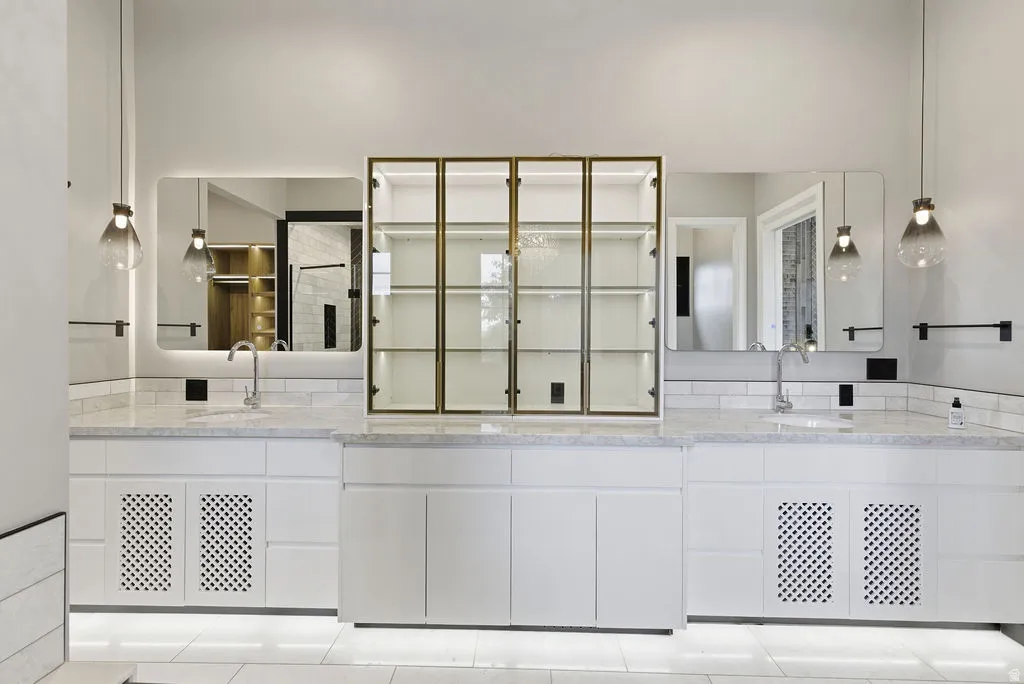 Dual vanity with white cabinetry, stone countertops, and subway tile backsplash