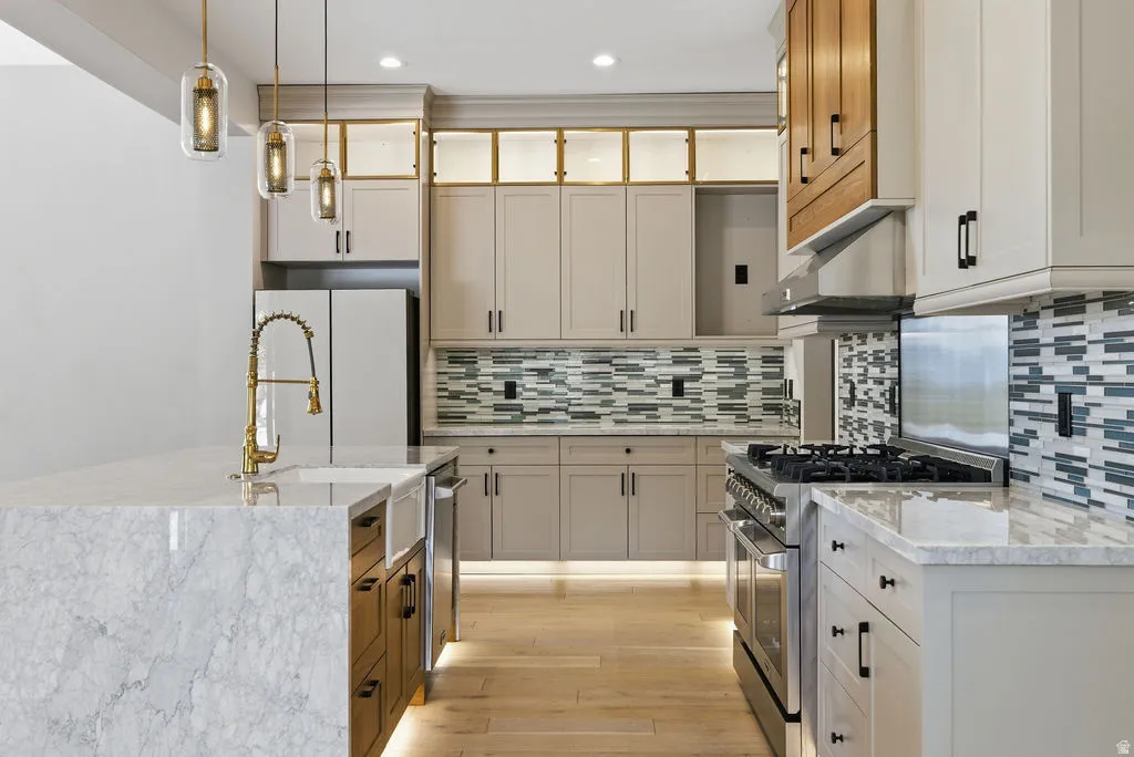Modern kitchen featuring a waterfall island with an integrated farmhouse sink and brass-finish faucet