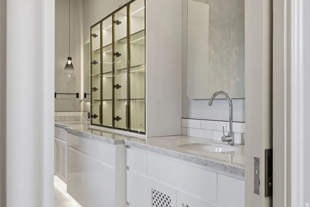 Bathroom vanity featuring a polished chrome faucet, under-mount sink, and light-toned countertop