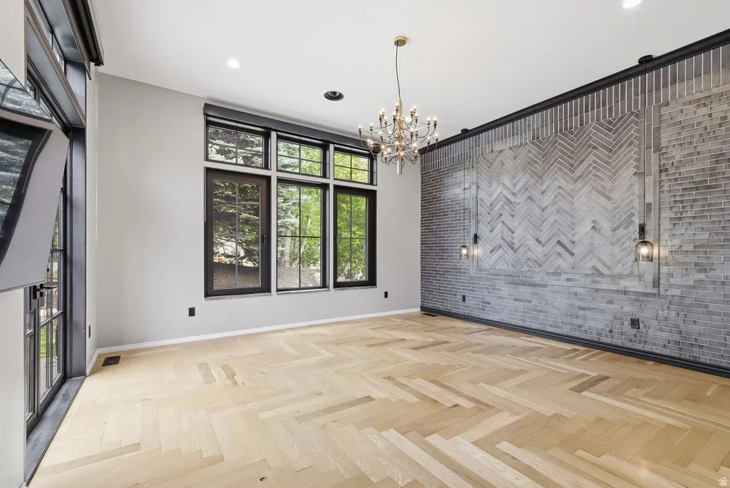 Herringbone wood-finish flooring complements a feature wall with gray brick and recessed lighting