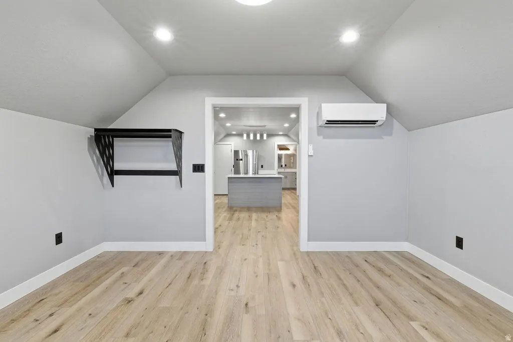 Attic space with light wood-finish flooring, white baseboards, and a wall-mounted shelving unit