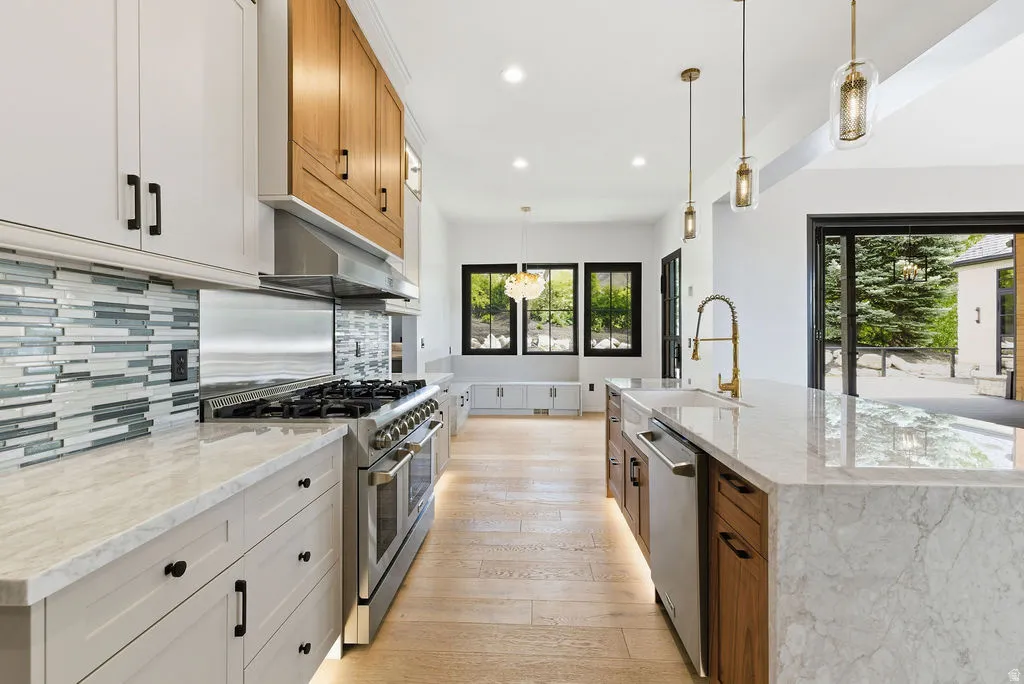 Gourmet kitchen featuring a waterfall island with integrated sink, gold-tone faucet, and pendant lighting