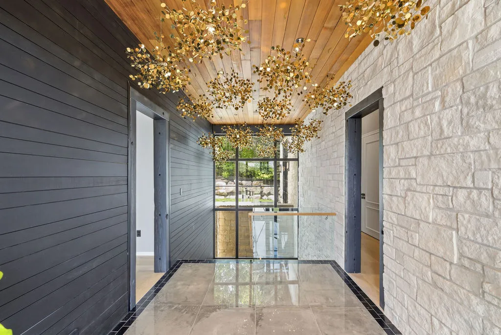 Entryway featuring a wood-finish ceiling, multiple gold-finish pendant light fixtures, and a glass railing