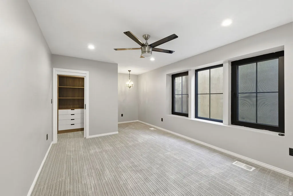 Room featuring three black-framed windows, a ceiling fan with light fixture, recessed lighting, and patterned carpeting