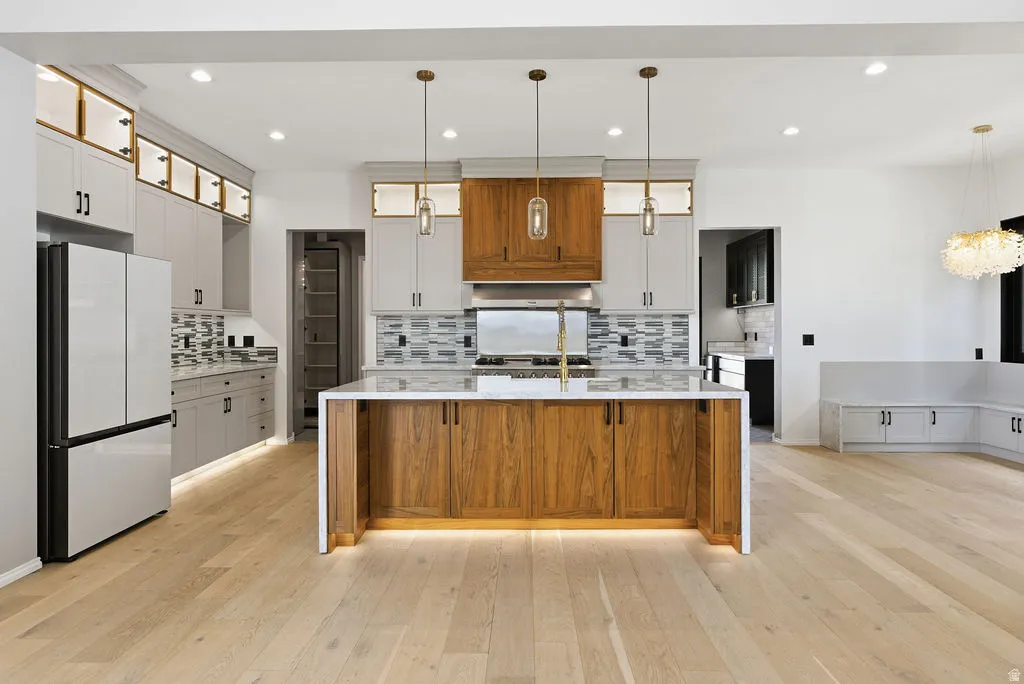 Contemporary kitchen featuring a large central island with wood-finish cabinetry, a white countertop, and under-cabinet lighting