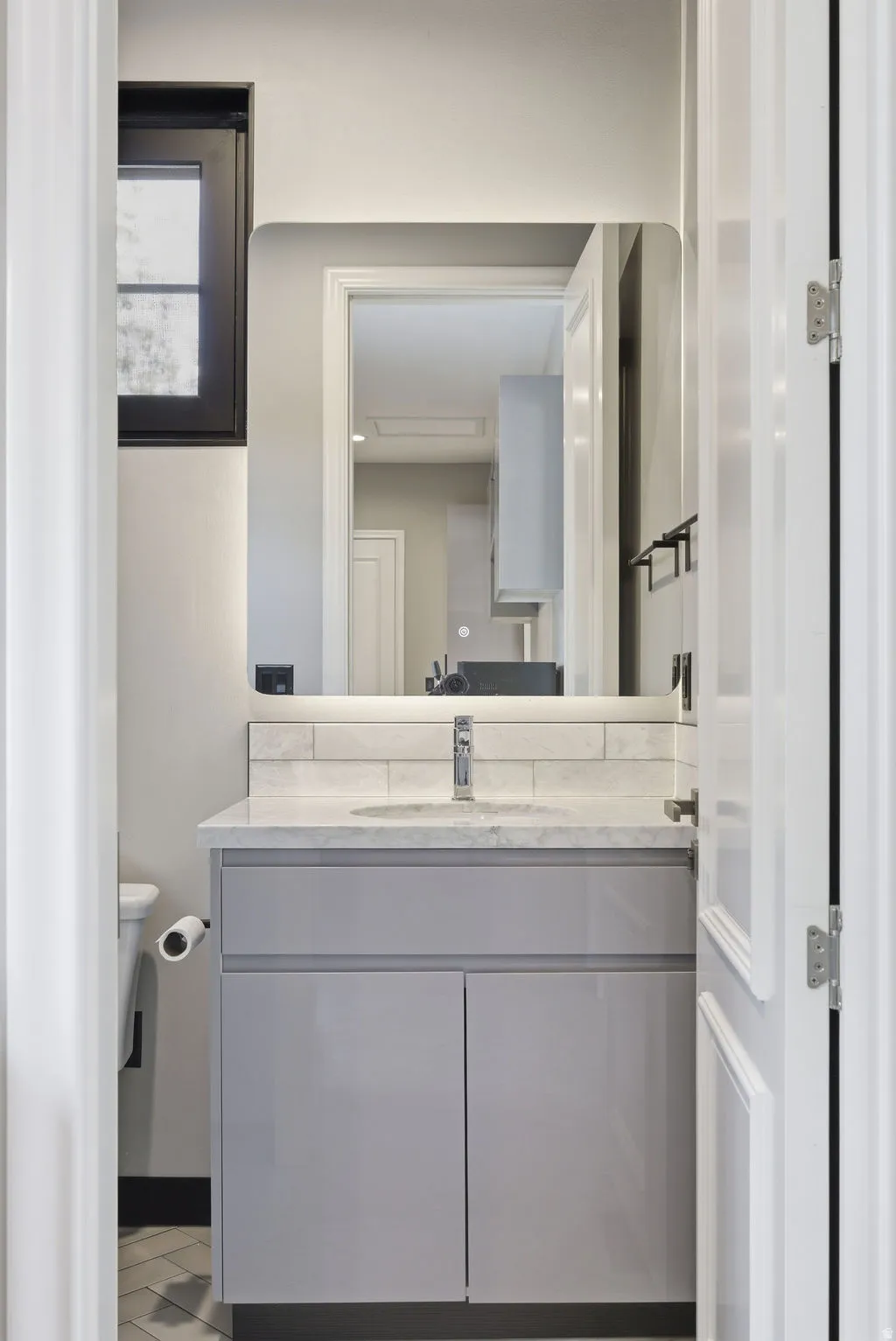 Modern vanity featuring a light gray cabinet with a white countertop and integrated sink