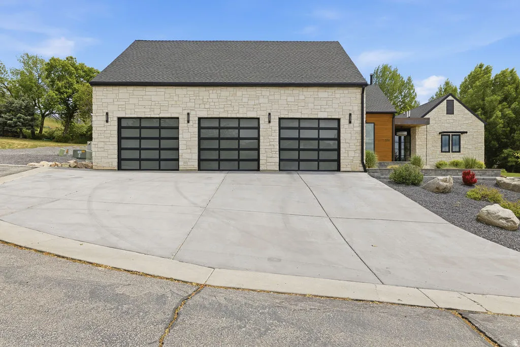 Stone veneer exterior with a dark shingle roof