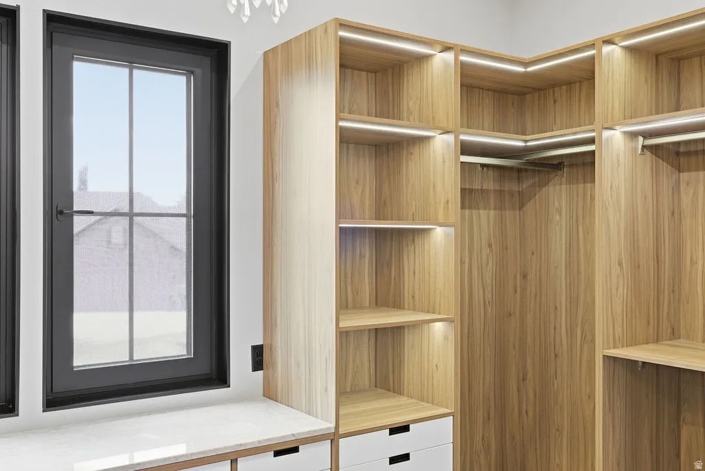 Custom closet system featuring wood-finish cabinetry and integrated lighting