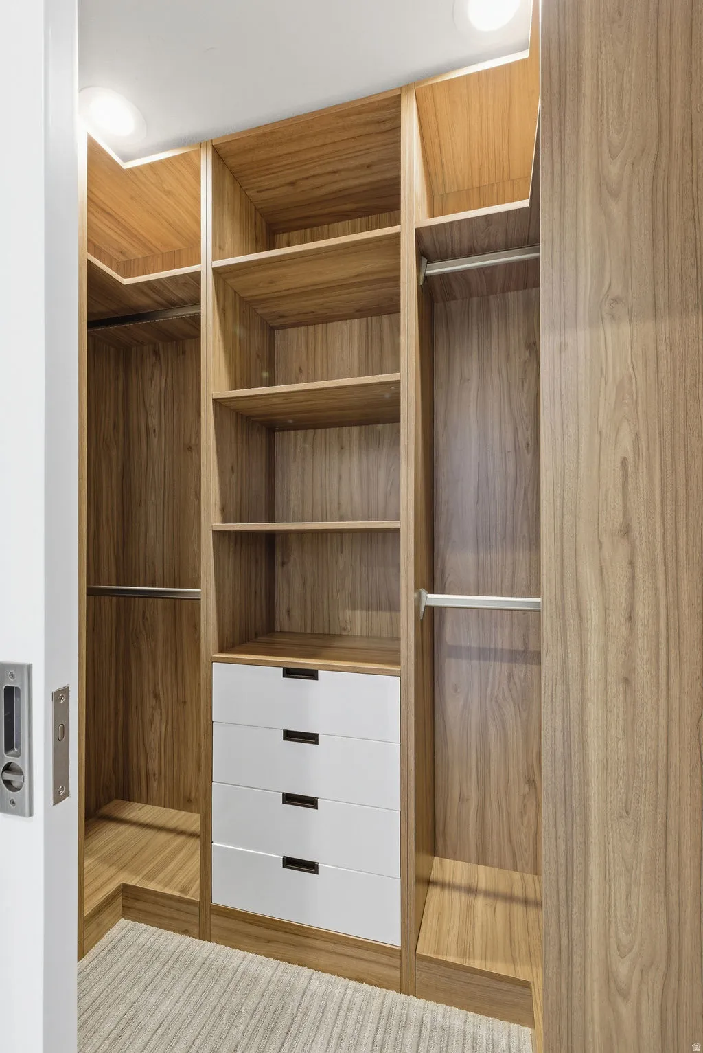 Custom closet system featuring wood-finish cabinetry, integrated shelving, hanging rods, and four white drawers with dark hardware