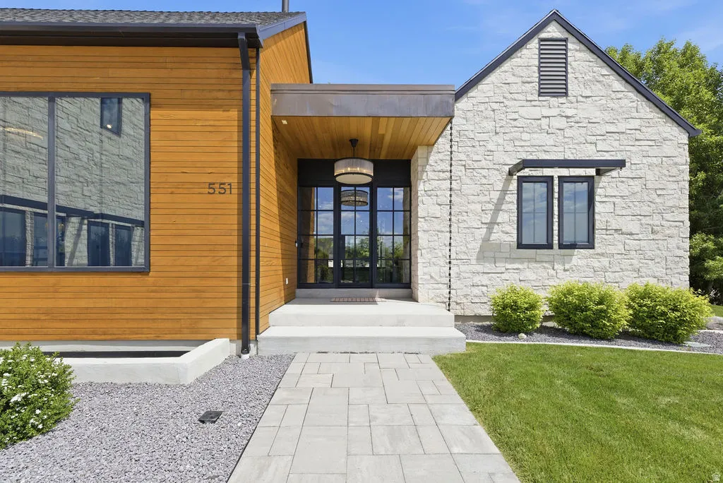 Modern exterior with a stone facade, wood siding, and large black-framed windows