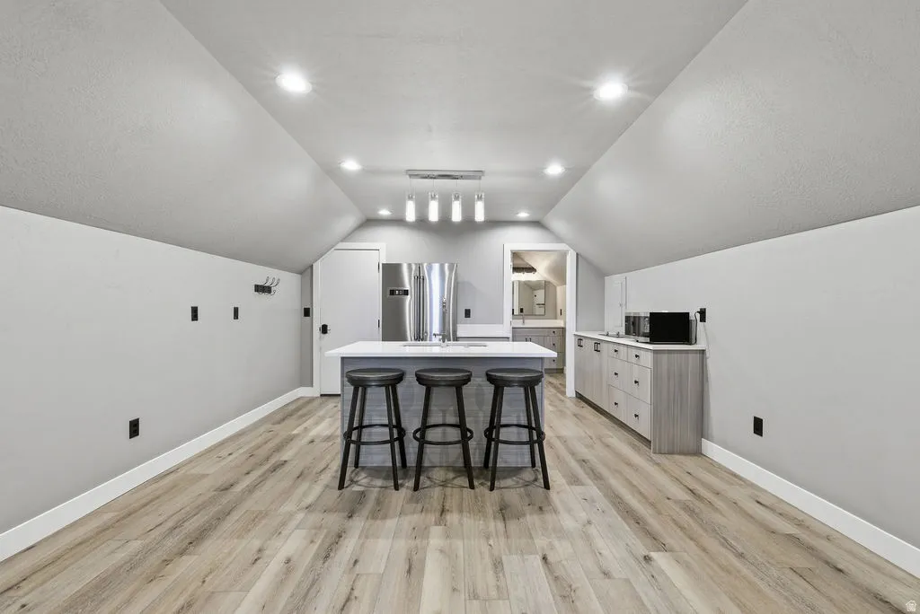 Spacious room featuring wood-finish flooring, recessed lighting, and a contemporary island with seating