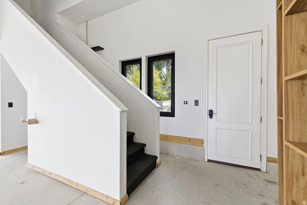 Carpeted stairs with a white banister and light wood trim, featuring twin windows with black frames