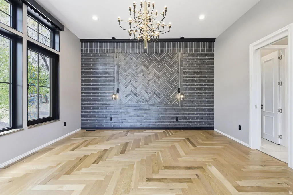 Herringbone wood-finish flooring provides a striking foundation for this room, complemented by a prominent gray brick accent wall