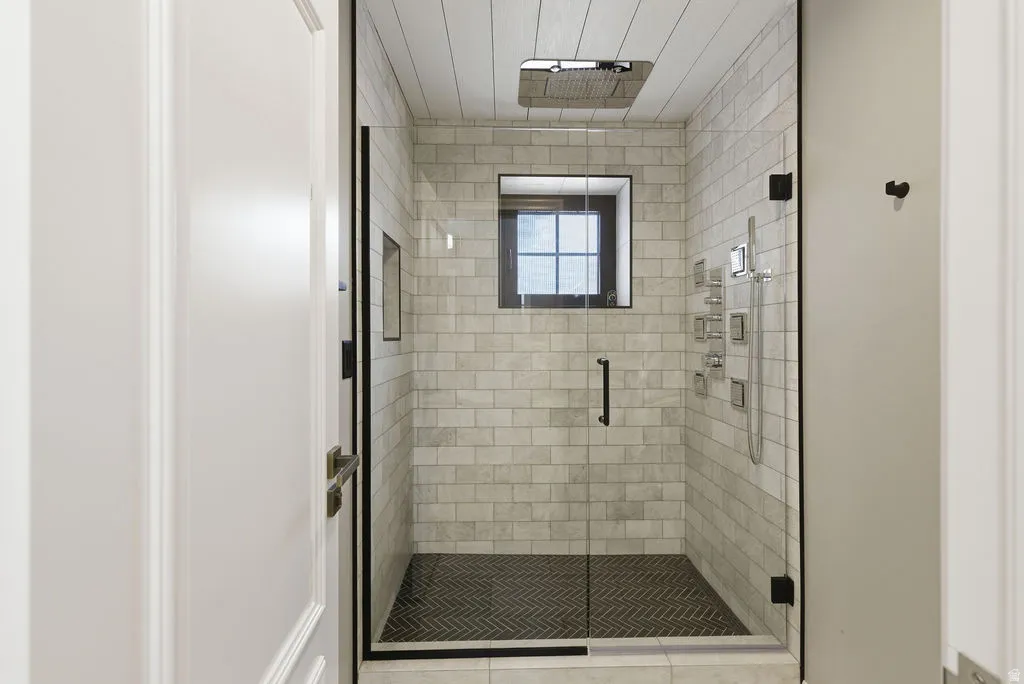 Glass-enclosed shower with subway tile walls and dark herringbone-patterned floor