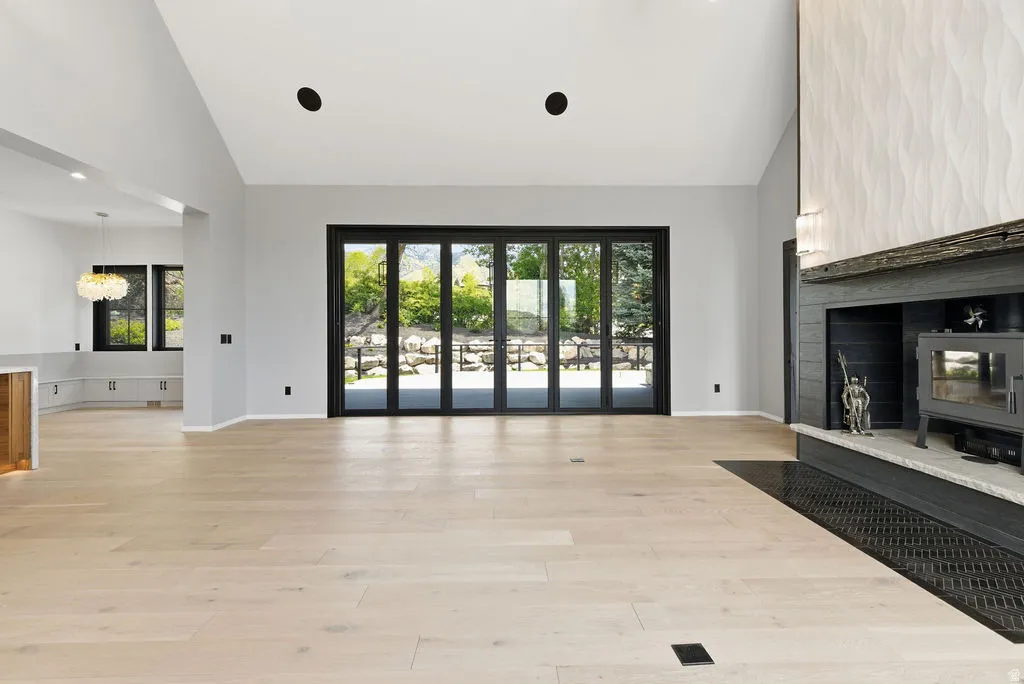Spacious living area featuring light wood-finish flooring, a vaulted ceiling, and a prominent fireplace with a textured surround