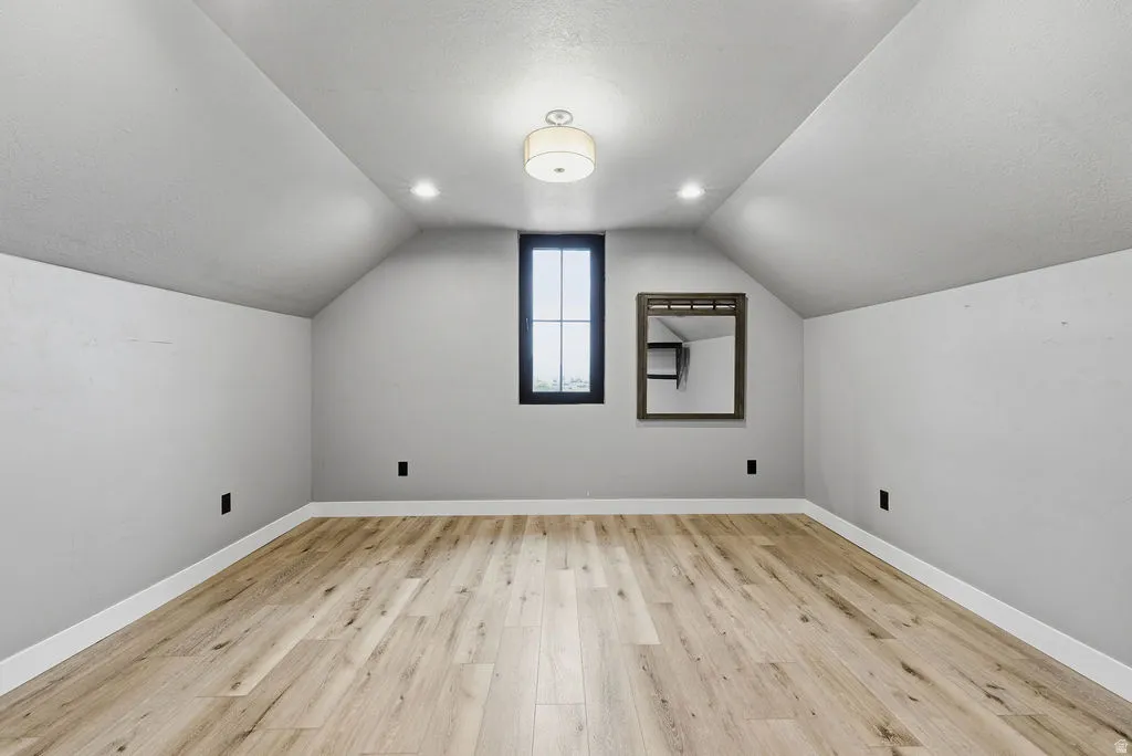 Room featuring a vaulted ceiling and light wood-finish flooring