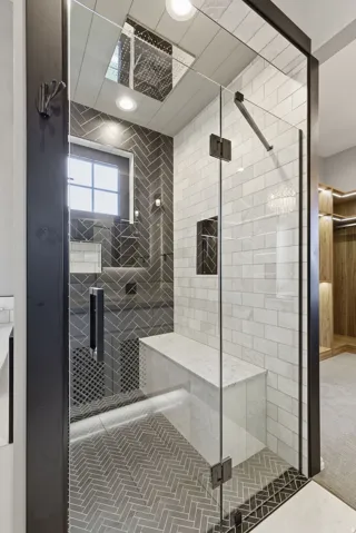 Glass-enclosed shower featuring a built-in bench, herringbone pattern tile flooring, and contrasting subway tile walls
