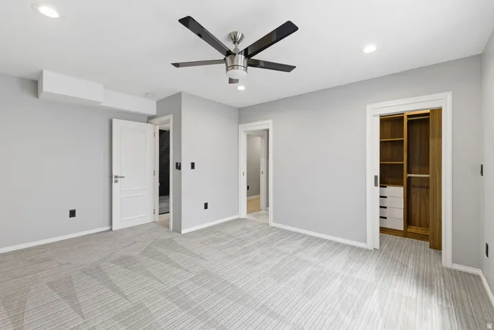 Spacious room featuring light gray walls, patterned carpeting, recessed lighting, and a modern ceiling fan