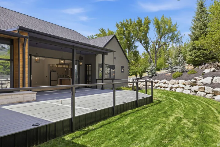 Spacious composite deck with stone accent planter, black railing, and integrated lighting