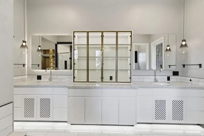Dual vanity with white cabinetry, stone countertops, and subway tile backsplash