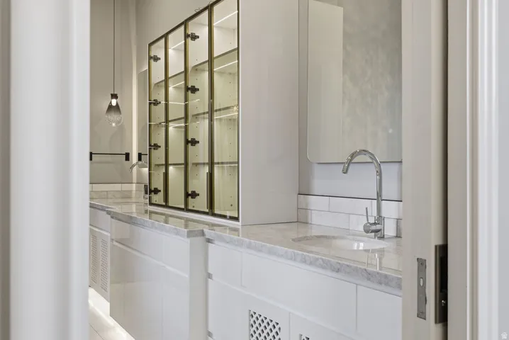 Bathroom vanity featuring a polished chrome faucet, under-mount sink, and light-toned countertop