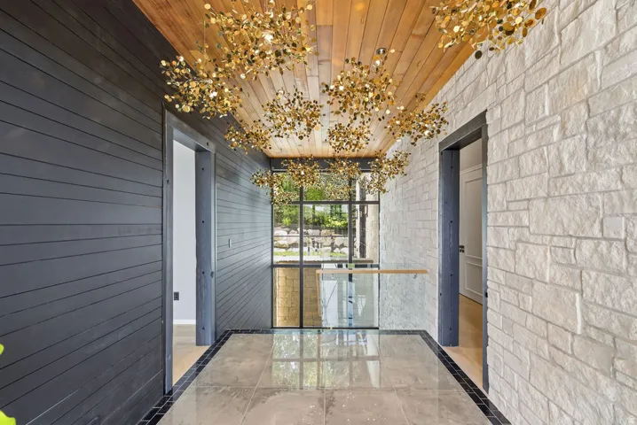 Entryway featuring a wood-finish ceiling, multiple gold-finish pendant light fixtures, and a glass railing