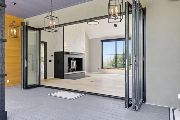 Expansive bi-fold glass doors opening to a covered porch with plank flooring