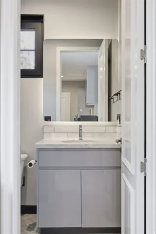Modern vanity featuring a light gray cabinet with a white countertop and integrated sink