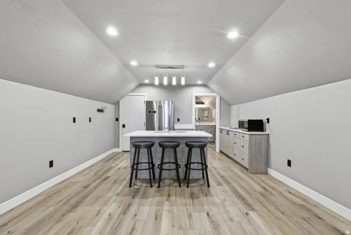 Spacious room featuring wood-finish flooring, recessed lighting, and a contemporary island with seating
