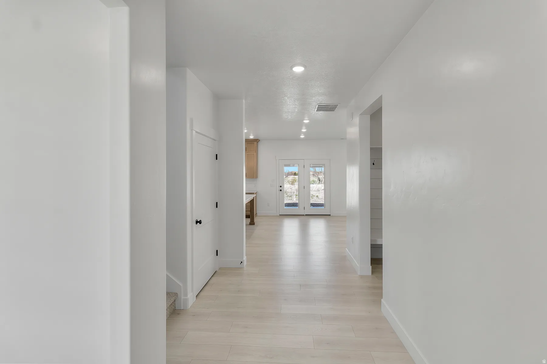 Hallway featuring light wood-finish flooring, recessed lighting, and white walls