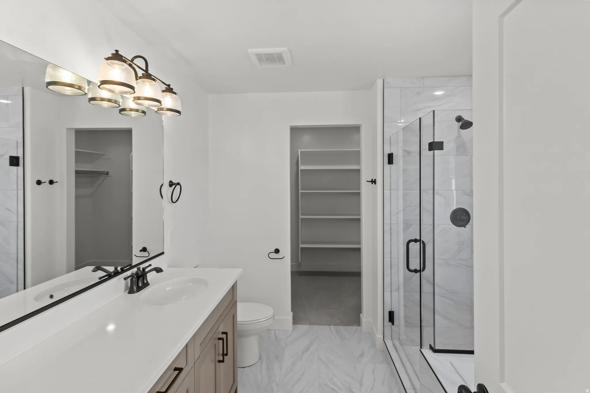 Contemporary bathroom featuring a wood-finish vanity with dual sinks, a large mirror, and a frameless glass shower with black fixtures
