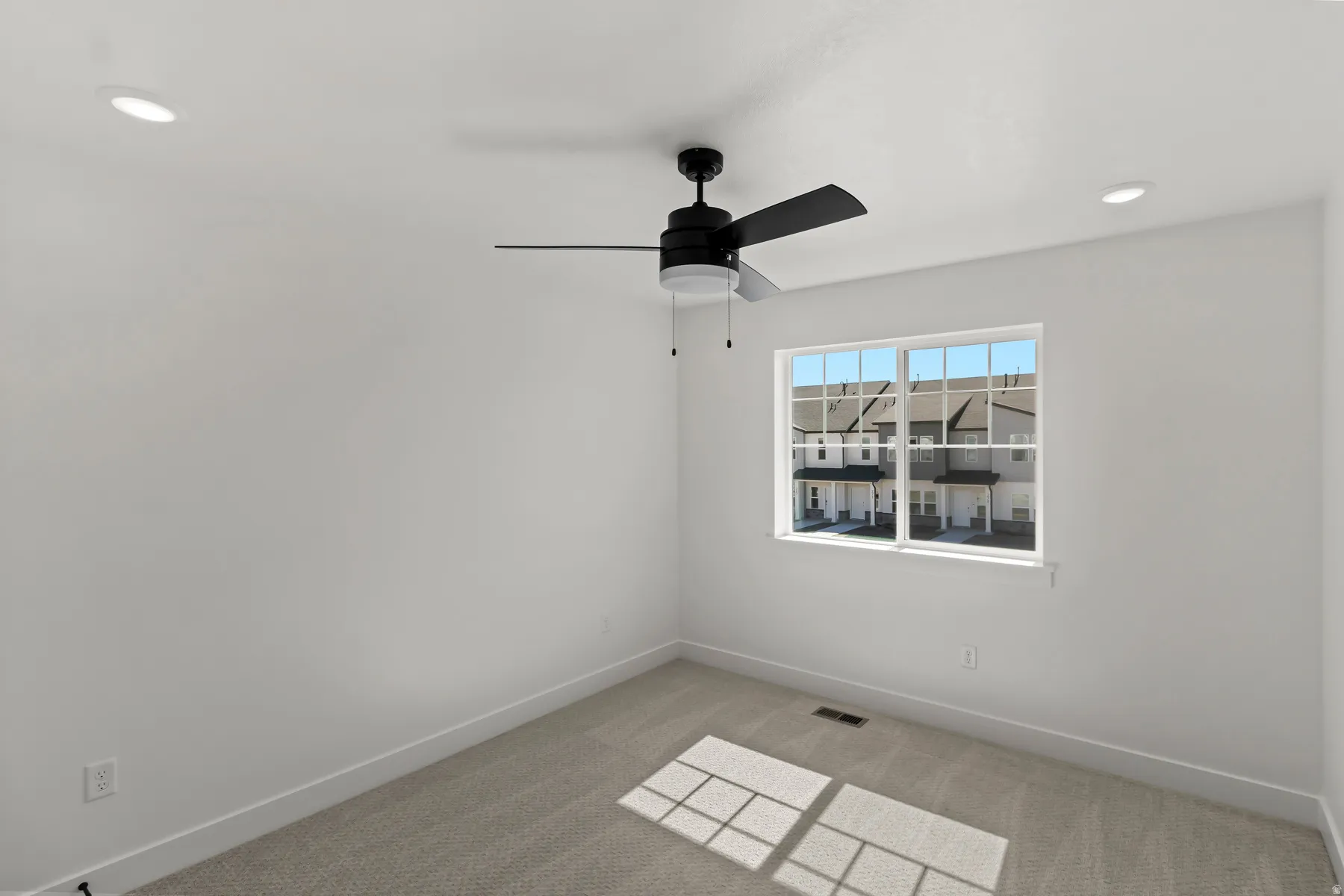 Bedroom featuring a black ceiling fan, two recessed lights, a window with grid panes, and neutral carpet flooring