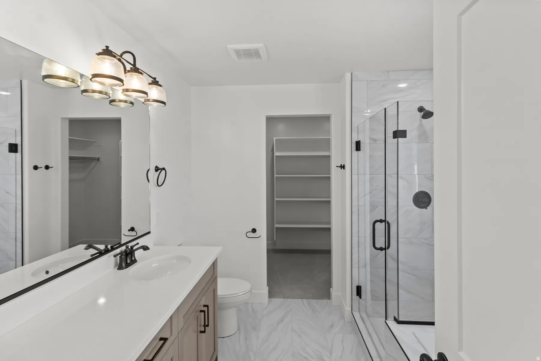 Modern bathroom featuring a double vanity with stone-finish countertop, dual sinks, and matte black fixtures