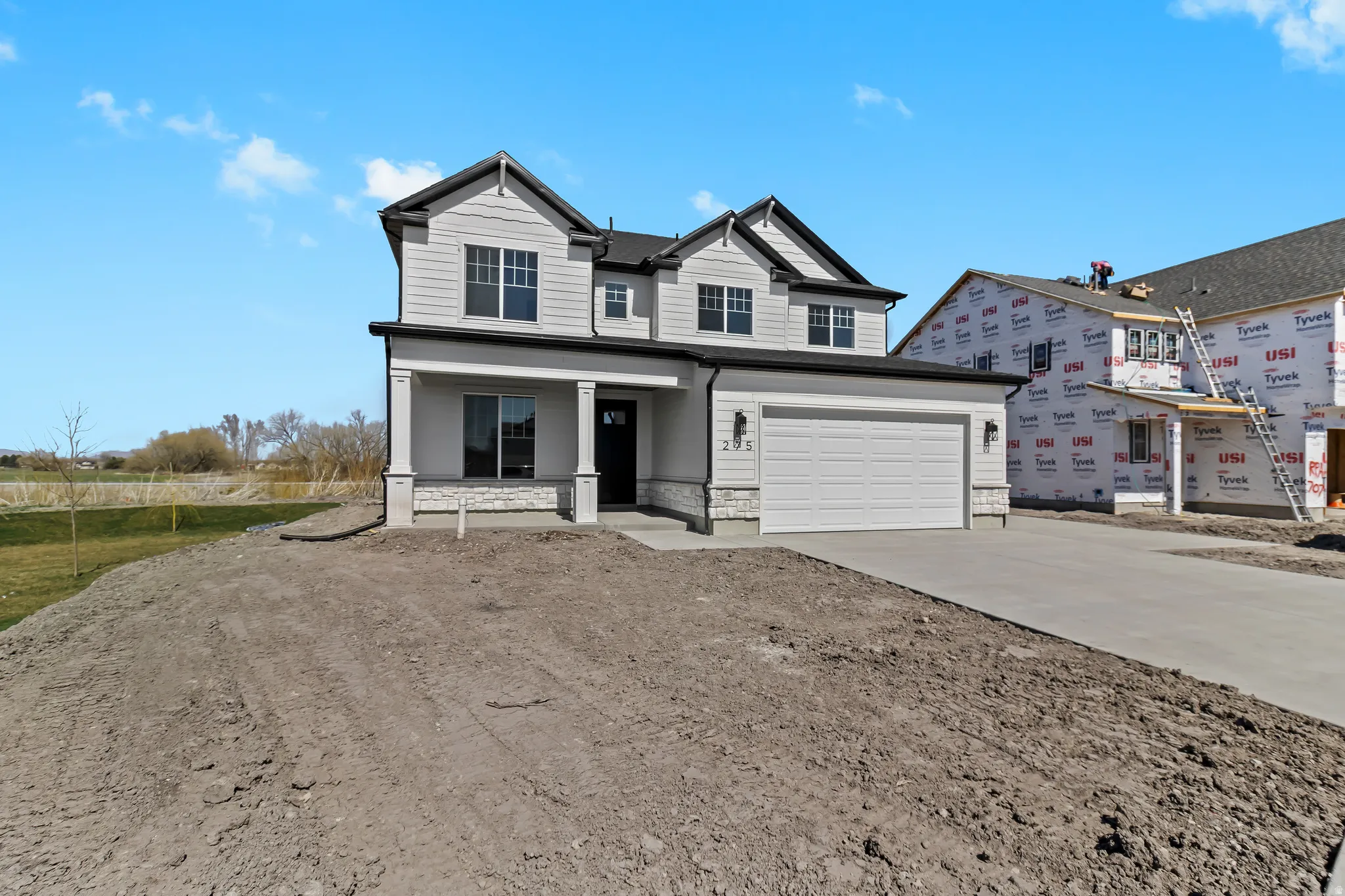 Contemporary-style residence featuring white siding, a contrasting dark roof, and a two-car garage with a concrete driveway