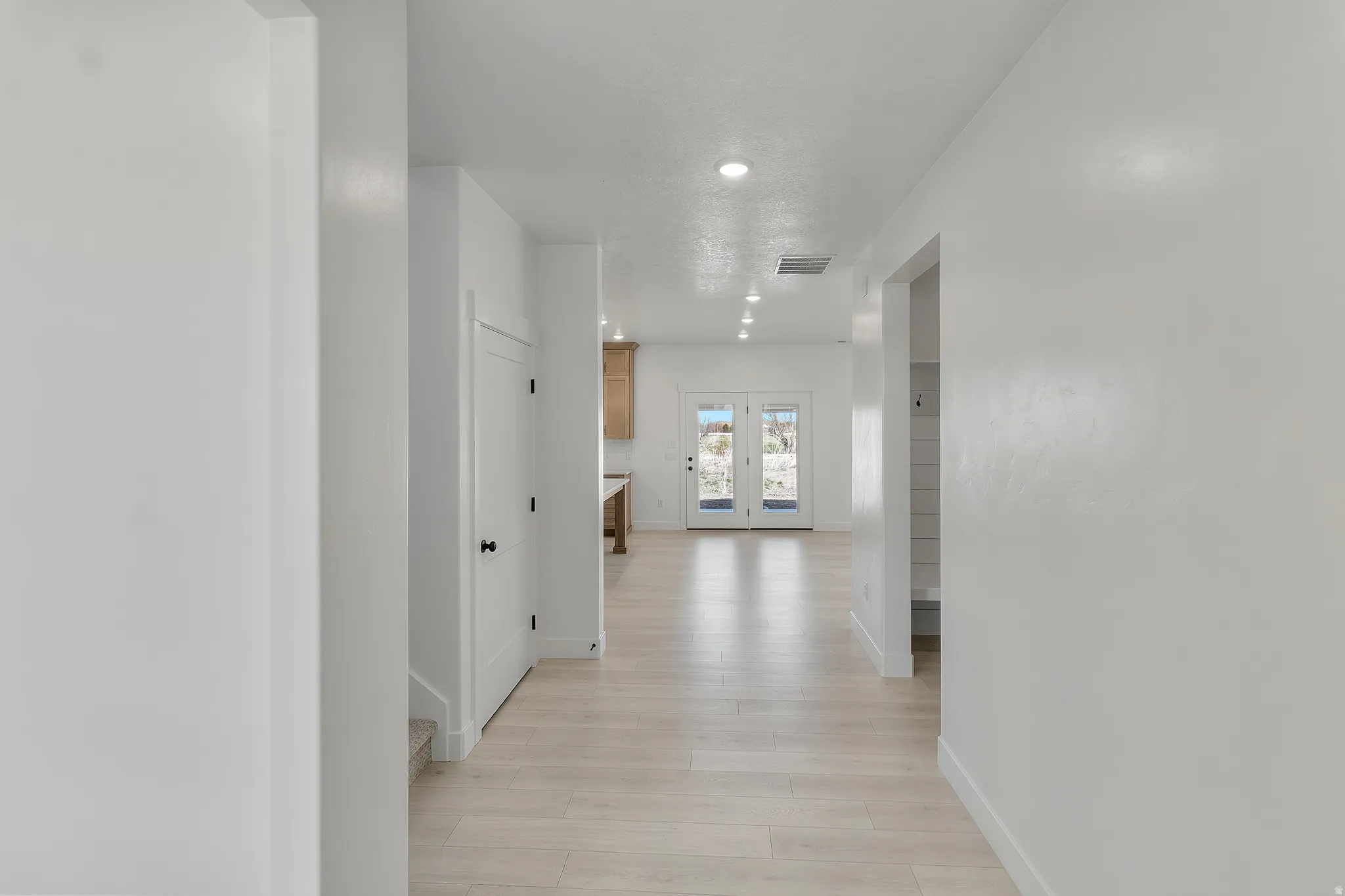 Hallway featuring light wood-finish flooring, white walls, and recessed lighting