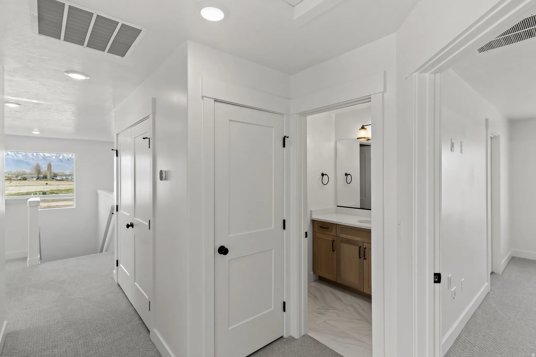 Hallway with light gray carpeting, recessed lighting, and a window offering a mountain landscape