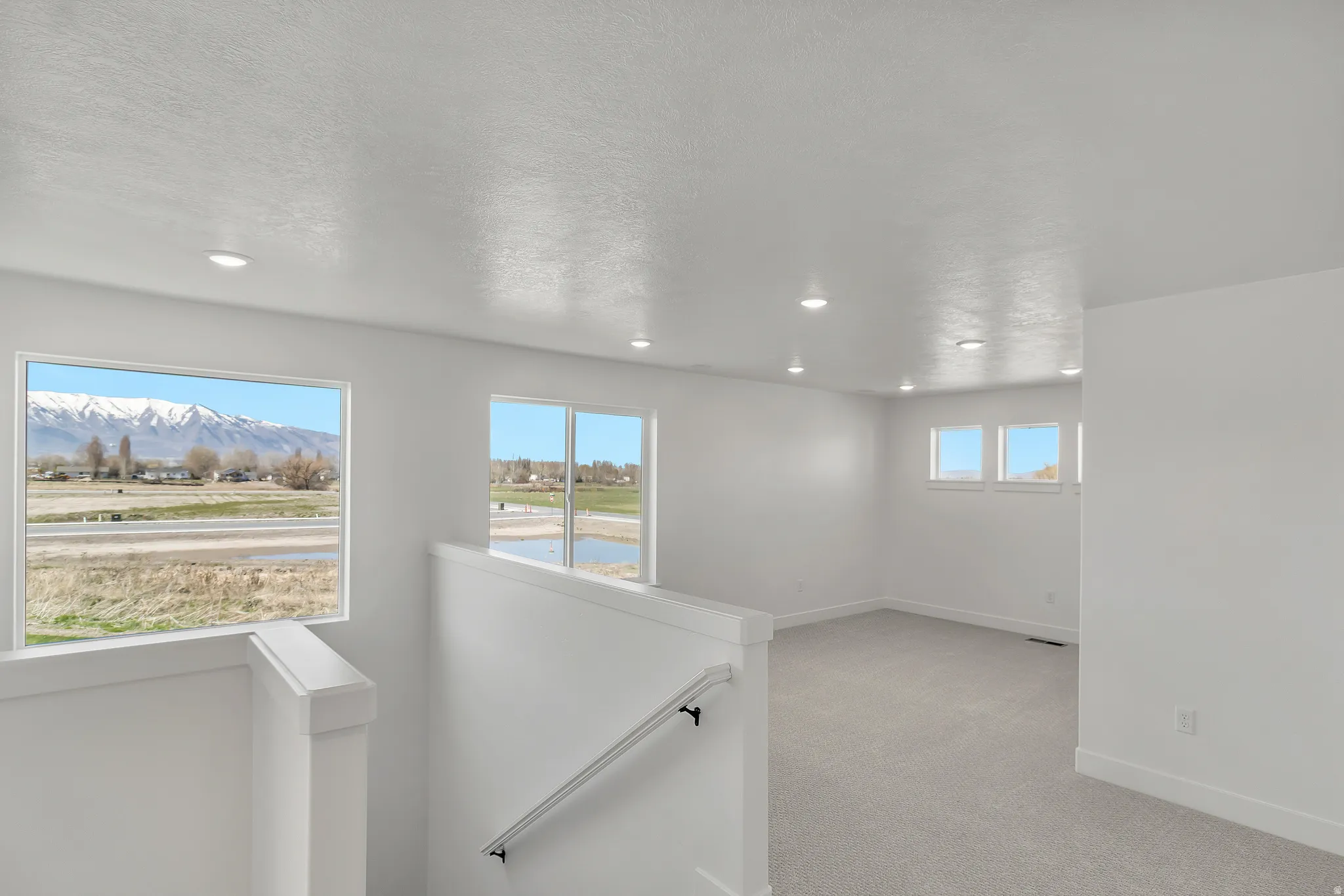 Upper-level living area featuring carpet flooring, recessed lighting, and multiple windows