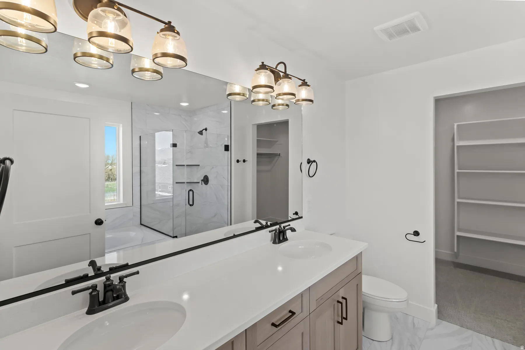 Bathroom featuring a double vanity with stone-finish countertop, matte black hardware, and an expansive mirror