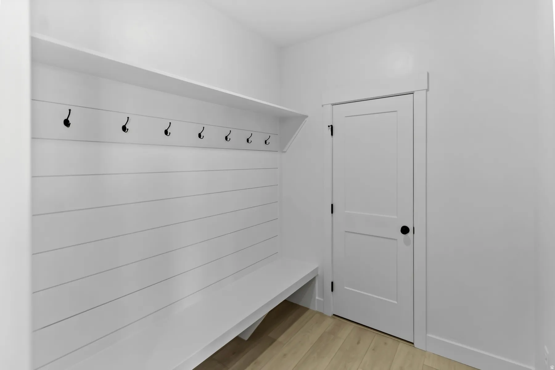 Entryway with shiplap accent wall, built-in bench, upper storage shelf, and multiple coat hooks