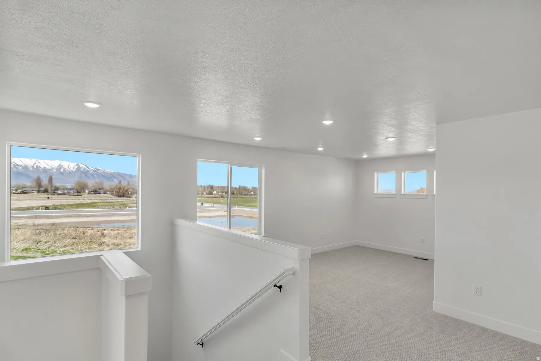 Spacious interior featuring a carpeted floor, recessed lighting, and multiple windows offering mountain and landscape scenery