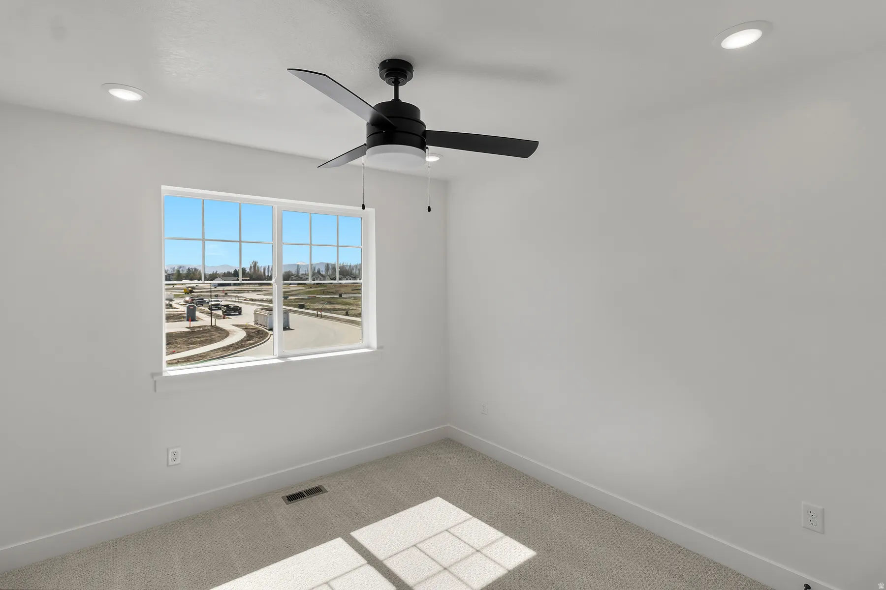 Room with a ceiling-mounted fan, recessed lighting, a large window, light-colored carpet, and white walls