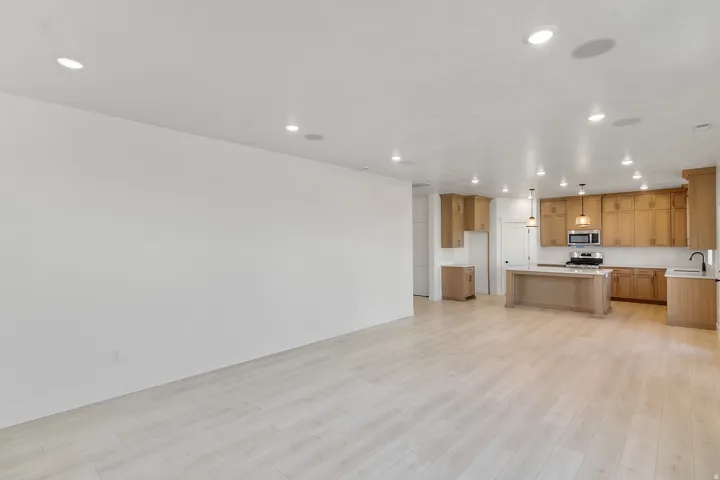 Open-concept living space featuring wood-finish flooring, recessed lighting, and a kitchen with light wood cabinetry